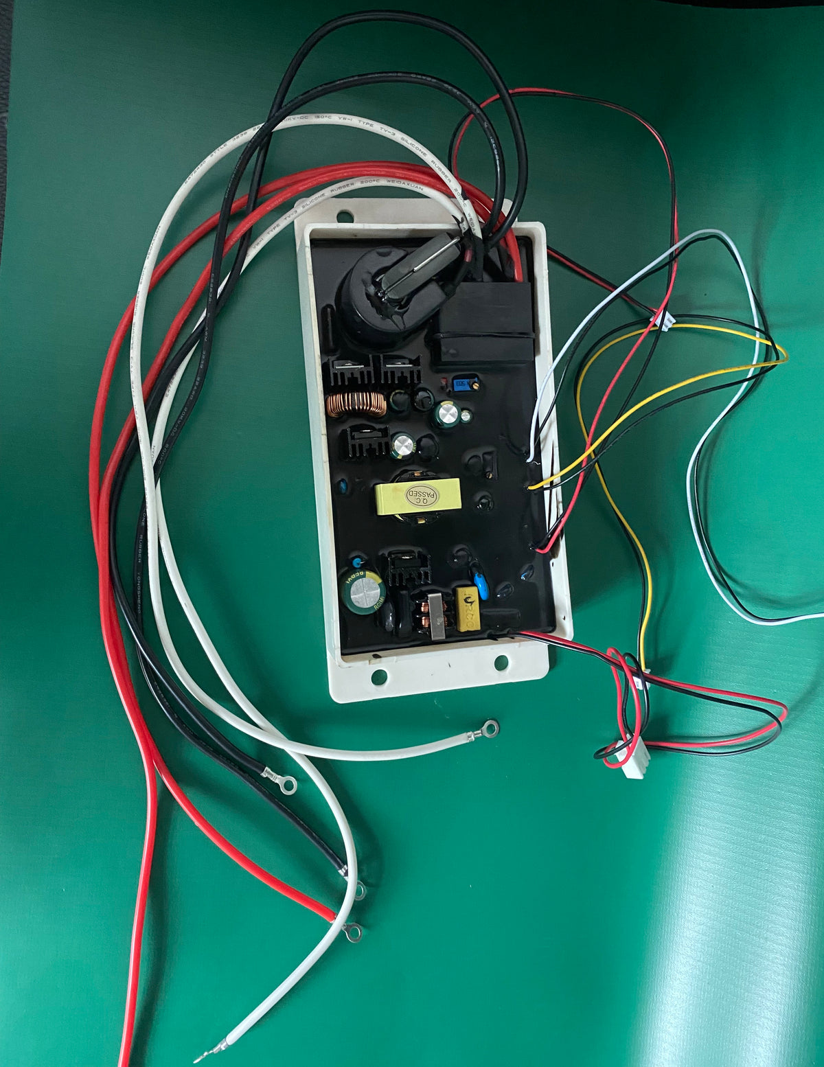    Engineering bench photograph of the KYOG220V09 open potted power module on an anti-static green work surface, displaying the comprehensive wiring harness including primary AC input leads, secondary fault status control cables, and silicone-jacketed high-voltage outputs ready for industrial HVAC air cleaner integration.
   